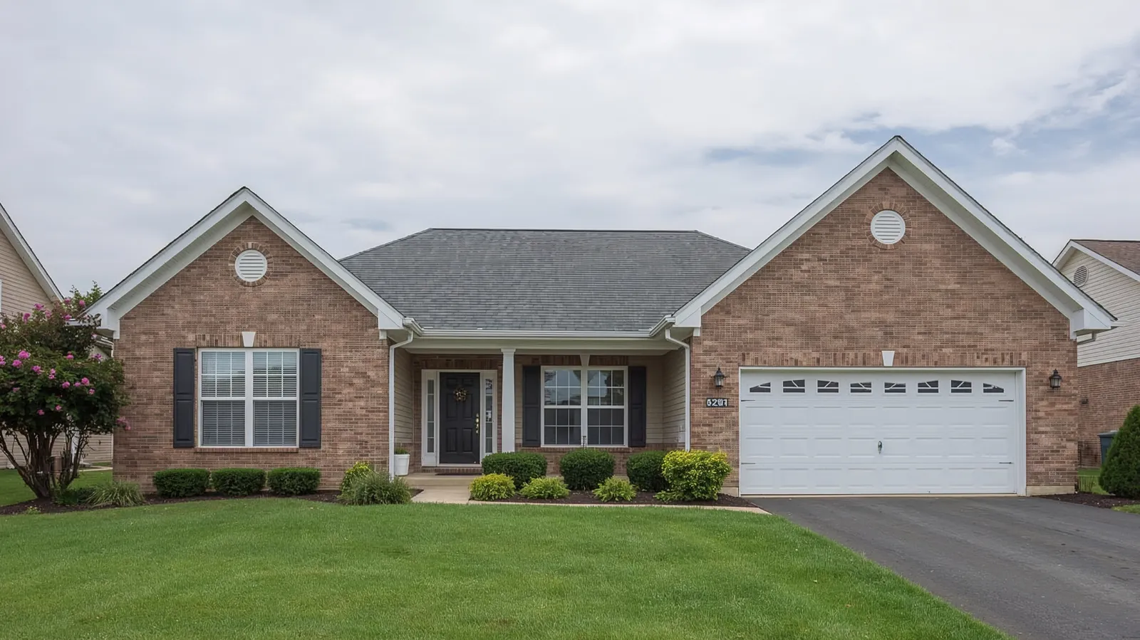 Gray asphalt shingle roof and white garage door on a brick ranch home
